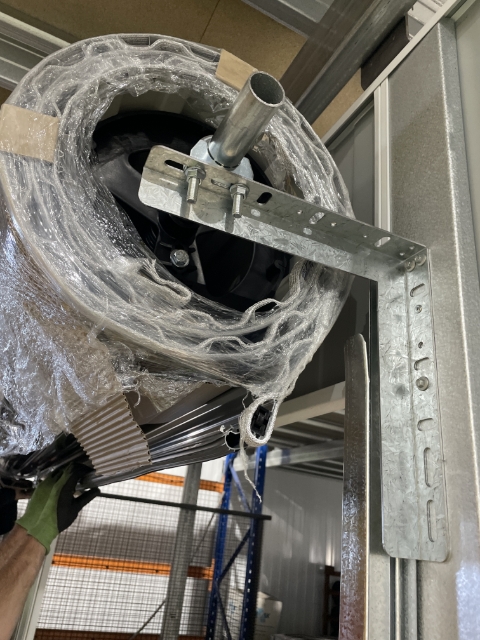 <p>Remove as much of the plastic from around the first layer of the door so you're able to unroll the door.</p><p>Make sure you don't release the door when doing this as it will spin back and the spring tension will be incorrect.</p>