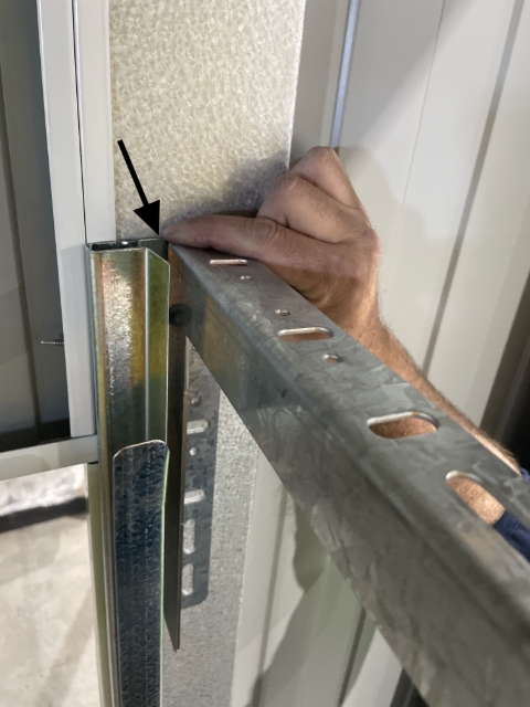 <p>Place the roller door mounting bracket flush with top and side of track, ensure the smooth side is facing the track and the side with the holes is away from the track.</p>