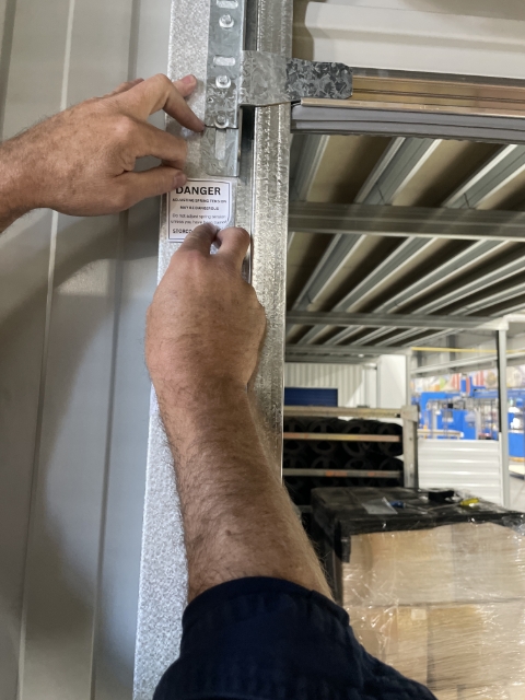 <p>Place your warning sticker under the mounting bracket on the left side mullion.</p>