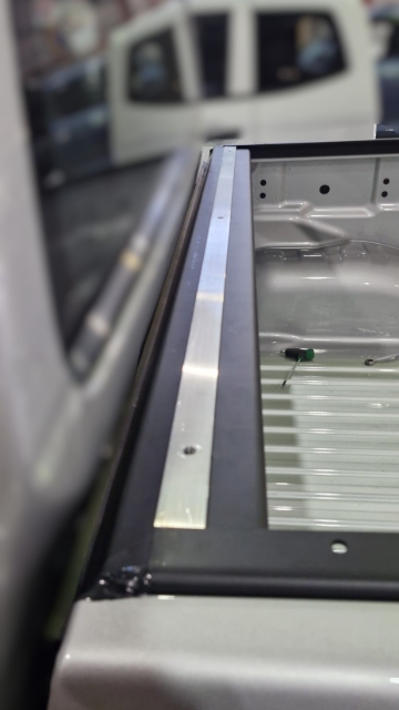 <p>Apply double-sided tape to the flat bar. Make sure the tape is secure across the entire length. Ensure the flat bar sits flush with the front of the side rails.</p>
