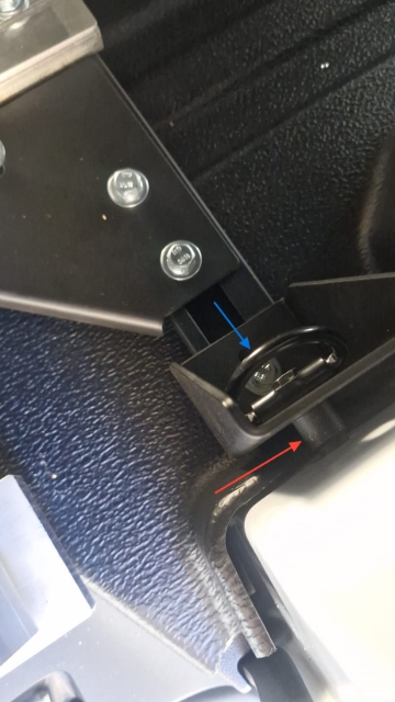 <p>Mount the rear brackets to the van’s tie-down points. Position the spacer behind the bracket (Red Arrow) and secure the tie-down point to the front of the bracket (Blue Arrow) using the factory hardware</p>