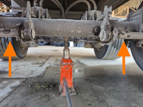 <p><strong>Axle</strong></p><p>The axle on a commercial trailer is a good place to jack as it provides a sturdy jack point.</p><blockquote><p>Please note that the <strong>only</strong> time that you might use one jack as shown in the photo is when the tub is completely empty or its a light trailer, and you need to jack up both wheels on the one axle.</p><p>If not, one or two jacks should be used at either end (orange arrows).</p></blockquote><p></p>