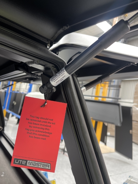 IMPORTANT WARRANTY TAG hung on rear gas strut mount