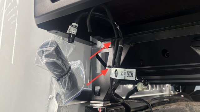 <p>Secure both breather lines to the front chassis mount using cable ties as shown.</p><blockquote><p><strong>CQC: Ensure each shepherd's hook is facing downward.</strong></p></blockquote><p></p>