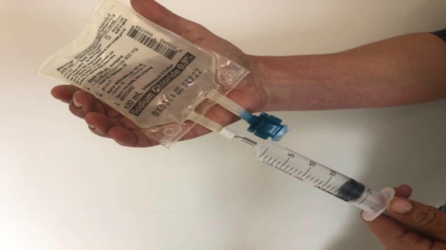 <p>Draw out 20 ml saline from bag like this.</p>