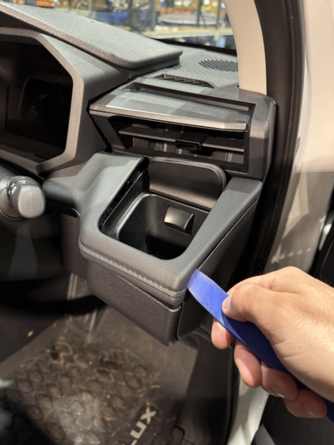 <p>Carefully, using the trim tool, begin by unclipping the top panel surrounding the cupholder.</p>
