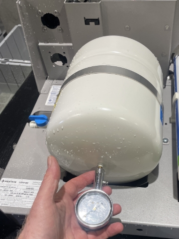 <ol><li>Carefully lie the unit down on its back panel to allow access to the bottom of the white storage tank.</li><li>Remove blue dust cover to give access to the schrader valve</li><li>Adjust tank pressure to 24 PSI using pressure gauge and bike pump</li></ol>