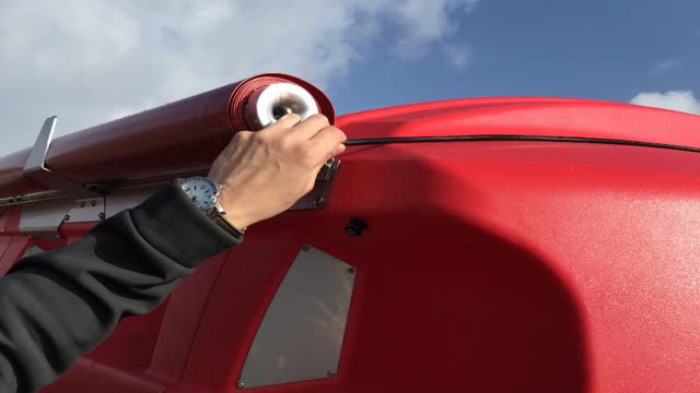 <p>At the front right of the spreader, release the bungee cord from the retaining lug.</p>