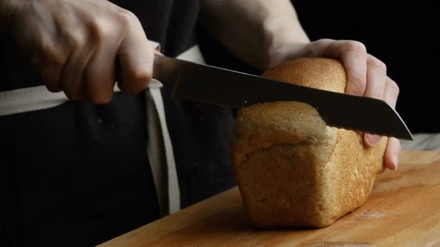 Place the loaf of bread on a chopping board, ensuring it is stable and won't move around.  Hold your bread knife with a firm but comfortable grip, making sure the serrated edge is facing downwards. Align the knife above the loaf where you want to make your first cut.