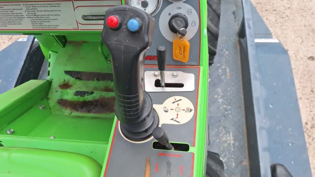 <p>The red and blue buttons operate the hydraulic drive to the attachment - opening/closing bucket, spinning the auger either diretcion, etc.
The lever in front of the joystick also operates this drive and when moved left and forward into the notch will provide continuous drive (handy when using the auger.)</p>
