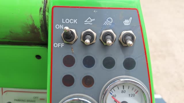 <p>Switches (up for 'On'):
Left switch is drive lock - handy for slippery areas and when loading the machine
Next switch over is for floating boom - handy for leveling/smoothing
Next is the work lights
And far right is your seat warmer!</p>
