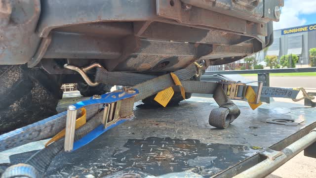 <p>Connect both ratchet straps diagonally across from the rear trailer anchor points to the front anchor points on the machine as shown.</p>
