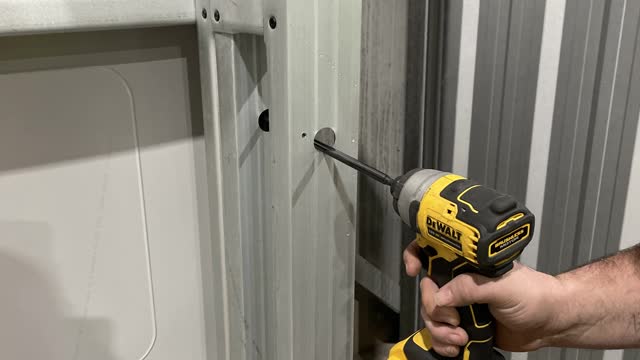<p>Using the holes provided screw in the shortest mullion to the side wall fixing it every hole provided plus adding two screws to the floor this will support your wall, insure the double wall Joyce is facing the inside where the roller door will be.</p>
