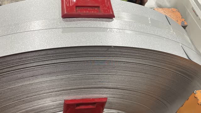 <p>Place red corners on coil. The top corner has to go on the backside of the decoiler, make sure the tail end of the coil is facing the top hat machine and that the material uncoils from the bottom.</p>